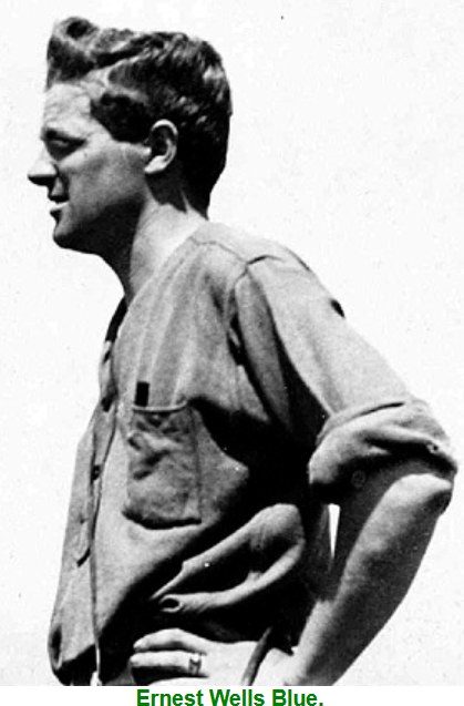 Ernest Wells Blue in profile, in a work shirt with rolled sleeves, hands on hips.