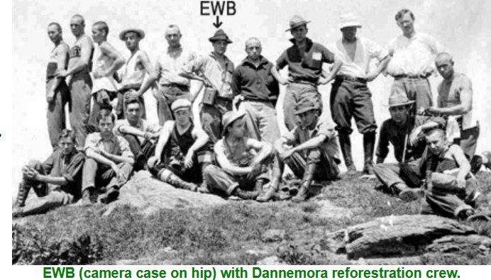 Group photograph of about twenty men on a rock outcrop, with an arrow marking Ernest Wells Blue standing at the centre in a campaign hat.